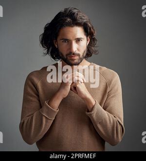 Je prends mon spirituellement très au sérieux. Studio photo d'un beau jeune homme priant sur fond gris. Banque D'Images