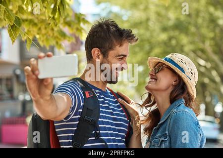 Je ne veux pas voir le monde avec qui que ce soit. Un couple de touristes heureux qui se pose pour un selfie tout en explorant une ville étrangère ensemble. Banque D'Images