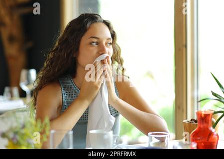 Femme nettoyant la bouche avec une serviette assise dans un restaurant Banque D'Images