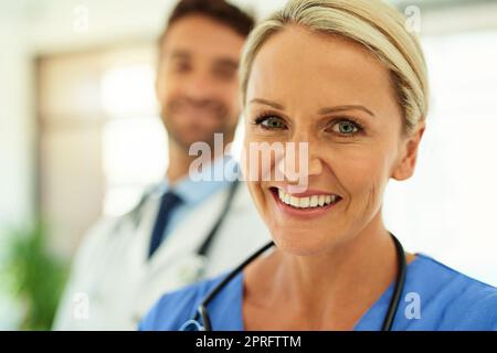 Mettez votre santé entre nos mains. Portrait de deux heureux professionnels de la santé se posant ensemble dans un hôpital. Banque D'Images