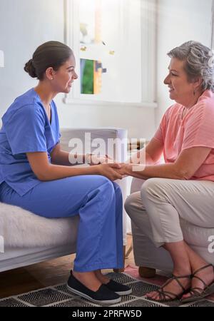 Malade toujours être autour pour aider. Une infirmière tenant les mains d'un aîné des femmes dans le confort. Banque D'Images