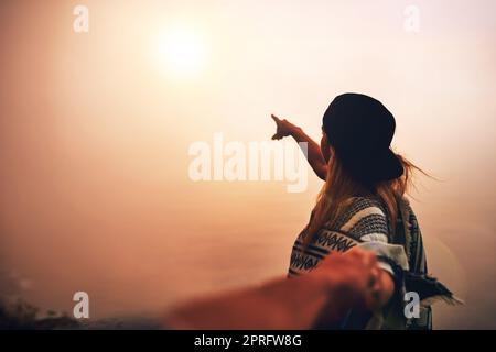Poursuivant l'horizon ensemble. Un jeune randonneur non identifiable montrant une vue brumeuse tout en logeant la main de son petit ami. Banque D'Images