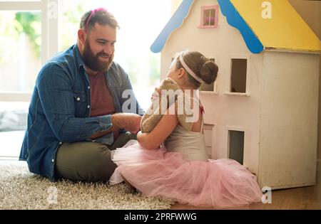 S'impliquer dans son jeu imaginatif. Une adorable petite fille et son père jouant avec une maison de poupées ensemble à la maison. Banque D'Images