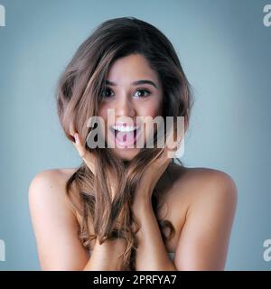 Des cheveux sains, beaux et brillants commencent maintenant. Photo studio d'une belle jeune femme posant sur un fond gris. Banque D'Images