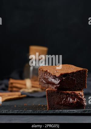 Morceaux de tarte au chocolat au brownie sur table noire, délicieux dessert Banque D'Images