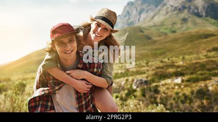 Je la porte mal n'importe quelle montagne pour faire son sourire. Portrait d'un jeune couple heureux profitant d'une promenade en pigeyback dans la nature. Banque D'Images