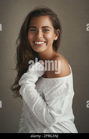 La beauté est dans l'œil du porte-bec. Portrait d'une belle jeune femme souriant sur fond marron en studio. Banque D'Images