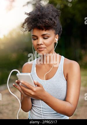 Il n'y a qu'une seule chose qui m'alimente pendant mes entraînements. Une jeune femme qui écoute de la musique sur son téléphone pendant une course. Banque D'Images