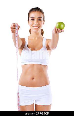 Mangez sage, lâcher une taille. Portrait d'une jeune femme en bonne santé tenant une pomme et un mètre ruban. Banque D'Images