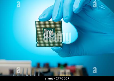 Ingénieur en électronique tenant la puce d'ordinateur sur fond bleu. Chipset de carte électronique pour carte mère PC. Puce UC. Composants électroniques. Matériel informatique. Puce de processeur informatique. Banque D'Images