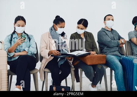 L'immigration pendant le covid avec des personnes voyageant et attendant dans un salon d'aéroport pendant la pandémie. Les réfugiés étrangers dans un centre de voyage public ou à la frontière portant des masques lors d'une épidémie de virus corona Banque D'Images