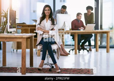 Elle maintient son équipe motivée. Portrait d'une femme d'affaires confiante avec son équipe travaillant en arrière-plan. Banque D'Images