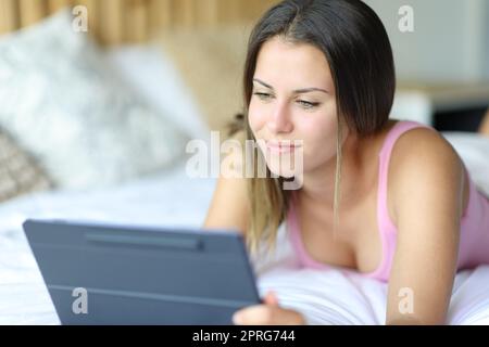 Bonne femme utilisant une tablette sur un lit à la maison Banque D'Images