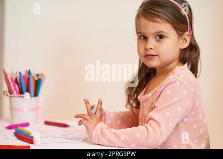 Petit artiste en train de se créer. Portrait d'une petite fille colorant dans une photo à la maison. Banque D'Images