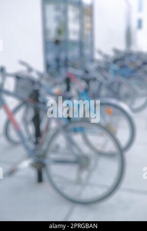 Prêt à rouler. Cliché flou d'une bicyclette à un porte-vélo dans une ville. Banque D'Images