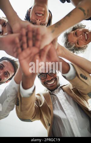 Chaque individu est un ingrédient de leur recette de succès. Portrait d'un groupe d'hommes d'affaires en bas angle mettant leurs mains dans un tas. Banque D'Images