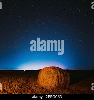 Starry Sky de nuit au-dessus de Haystacks dans le champ agricole d'été. Étoiles de nuit au-dessus du paysage rural avec balles de foin après la récolte. Concept agricole Banque D'Images