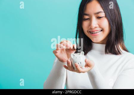 femme tenant une tirelire sur les mains et mettant de la monnaie Banque D'Images