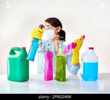 Prêt à s'attaquer à la graisse et à la grime. Une jeune femme qui tient plusieurs bouteilles de détergents. Banque D'Images