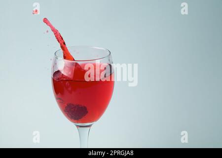 framboise éclaboussant dans un verre de vin rouge jus de boisson eau de destruction goutte sur fond blanc Banque D'Images