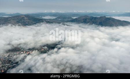 Au-dessus des nuages. Paysage de montagne en couches avec une ville de Carpates, Ukraine. Télécharger l'image Banque D'Images