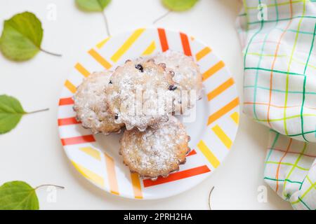 Cupcakes colorés sur une plaque avec des feuilles vertes, close-up. Banque D'Images