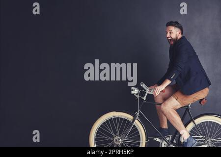 Les vélos lui emplir de joie enfantine. Un jeune homme branché à vélo en studio. Banque D'Images