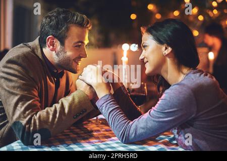 Vous êtes tout ce qui compte dans ce moment. Un jeune couple affectueux ayant un dîner romantique dans un restaurant. Banque D'Images