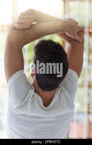 Réveillez-vous et soyez génial. Vue arrière d'un homme qui s'étire le matin à la maison. Banque D'Images