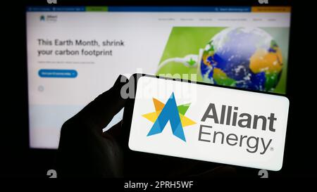 Personne tenant un smartphone avec le logo de la société américaine alliant Energy Corporation à l'écran devant le site Web. Mise au point sur l'affichage du téléphone. Banque D'Images