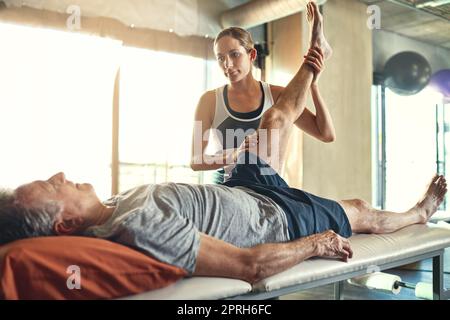 Faire de son mieux pour améliorer la qualité de vie de ses patients. Un homme âgé traité par un physiothérapeute. Banque D'Images