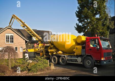 Pompe à béton montée sur camion pompant le béton derrière une maison unifamiliale Banque D'Images