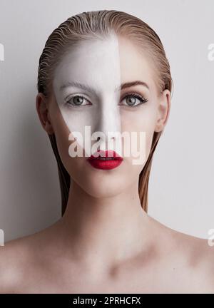 Osez être différente. Une belle femme portant la peinture de visage et rouge à lèvres sur un fond Uni. Banque D'Images