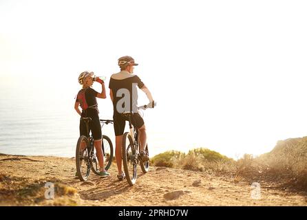 Le trajet est difficile mais la vue est superbe. Un jeune couple admirant la vue depuis une colline tout en faisant un tour en vélo. Banque D'Images