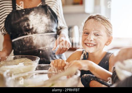 Ils faisaient des souvenirs, pas un gâchis. Portrait d'une petite fille qui s'amuse tout en cuisant avec sa famille dans la cuisine. Banque D'Images