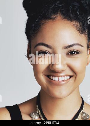 Le vrai bonheur est la vraie beauté. Portrait studio d'une jeune femme heureuse posant sur un fond gris. Banque D'Images