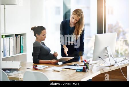 Jetez un œil à vous-même. Une femme d'affaires enceinte et un collègue utilisent une tablette numérique dans leur bureau. Banque D'Images