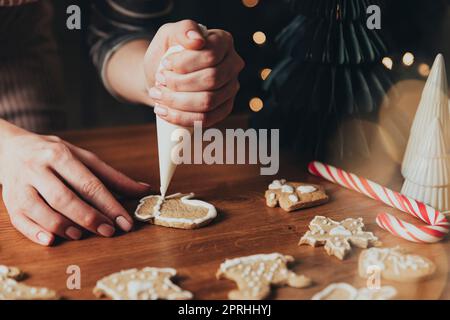 Noël, préparation de la nourriture du nouvel an. Biscuits de pain d'épice décorant avec glaçage Banque D'Images