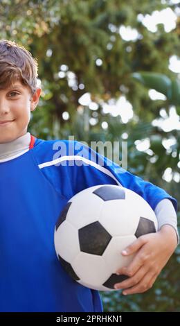 Une balle est tout ce dont il a besoin. Portrait court d'un jeune garçon tenant un ballon de football Banque D'Images