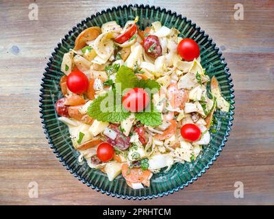 Salade de chicorée, pommes, tomates et carottes tranchées sur une assiette en verre vert foncé Banque D'Images