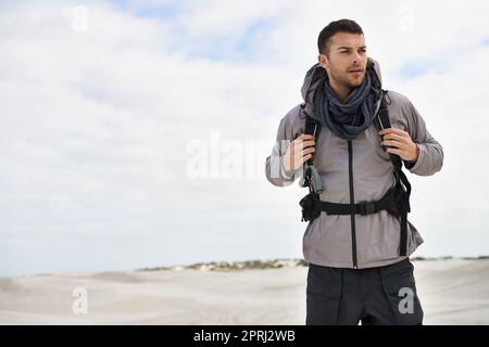 S'attaquer à tous les types de terrain. Un jeune randonneur mâle marchant le long des dunes de sable Banque D'Images