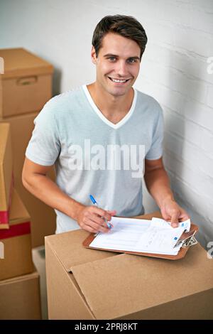 Que le déballage commence. Un jeune homme signe un document pour la livraison de ses boîtes en carton Banque D'Images