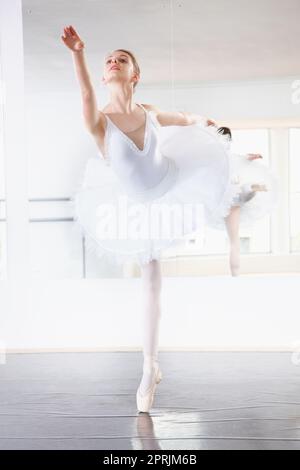 Ballerine statuesque. Prise de vue en longueur d'une répétition de ballerine dans un studio avec un miroir derrière elle Banque D'Images