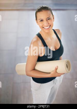 La forme physique est un mode de vie. Portrait court d'une jeune femme portant son tapis d'exercice sur le chemin du yoga. Banque D'Images