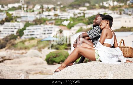 Couple noir, pique-nique d'été sur la plage et rendez-vous romantique avec amour, détendez-vous et collage sur une journée ensoleillée en plein air ensemble. Jeunes, souriants et heureux peuple africain américain appréciant un séjour de qualité sans souci sur la côte Banque D'Images