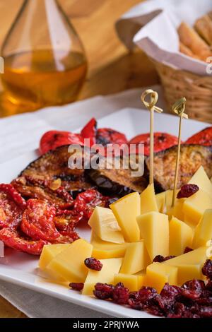 Vue rapprochée de divers hors-d'œuvre pour le vin : fromage, tomates séchées au soleil, aubergine rôtie, poivron, harnachement et canneberge séchée Banque D'Images