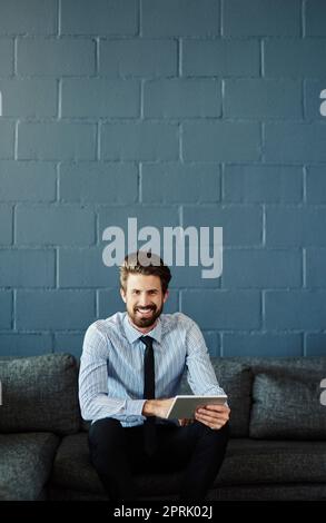 La technologie sans fil est ma méthode de travail préférée. Portrait court d'un jeune homme d'affaires charmant utilisant sa tablette numérique au bureau. Banque D'Images