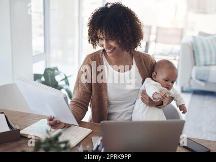 Faire de l'équilibre un jeu d'enfant. une jeune femme utilisant un ordinateur portable tout en prenant soin de son adorable bébé fille à la maison Banque D'Images