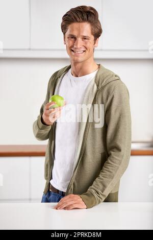 Commencer sa journée en toute santé. Portrait d'un beau jeune homme mangeant une pomme Banque D'Images