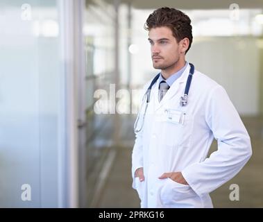 Considérant les options de traitement de ses patients. un beau jeune médecin Banque D'Images